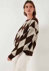 Braun in krem vzorčen pulover z rombom, z udobnim krojem, rebrastimi manšetami in mehkimi, teksturiranimi materiali.
