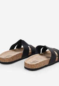 Black slip-on sandals with two wide straps, cork footbed, and textured rubber sole. The inner footbed is a light tan color.