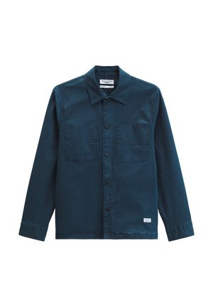 Veste bleu foncé à boutons, avec deux poches poitrine à l'avant, manches longues et col, posée à plat sur un fond blanc.