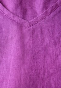 Lila linne tyg med en subtil textur och en V-formad halsringning. Har ren sömnad längs kanterna.