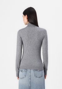 Gray turtleneck sweater made of soft knit material, featuring long sleeves and a fitted design, paired with a light blue denim skirt.