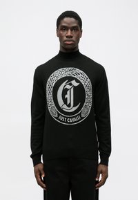 Pulover negru din tricot, prezentând un logo circular gri cu textul "Just Cavalli". Design cu guler înalt, cu manșete și tiv cu nervuri. Textură netedă.