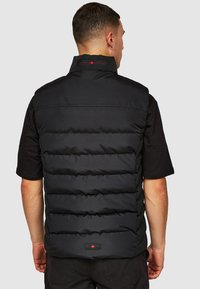Zwarte puffer gilet met horizontaal gewatteerde secties, hoge kraag en klein rood esdoornbladlogo. Glad textuur en lichtgewicht ontwerp.