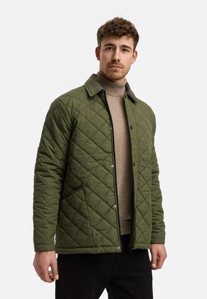 Quilted green jacket with a corduroy collar, featuring a front zipper, snap closures, and two side pockets. Worn over a beige sweater.