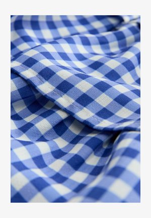 Zils un balts pārklāts audums ar mīkstu tekstūru, kurā ir mazi kvadrāti maiņus zilās nokrāsās. Iekļauj izpūrušu malas detaļu.