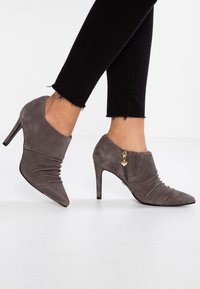 Grå mockahöga stövletter med sidsköld, veckat material framtill och spetsig tå. Stylade med svarta korta byxor.