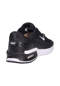 Zapatilla deportiva negra con parte superior texturizada, acentos blancos y una unidad de amortiguación de aire visible. Cuenta con una suela de goma con un diseño estampado.