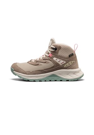 Beiger und hellbrauner High-Top-Wanderschuh mit weißen Schnürsenkeln, hellgrüner Sohle, pinker Zuglasche und KEEN-Logo an der Seite.