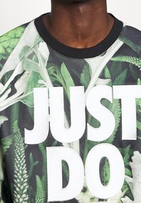Felpa grafica con stampa all-over di piante verdi, colletto a costine nero e grande testo bianco che recita "JUST DO." Tessuto testurizzato.
