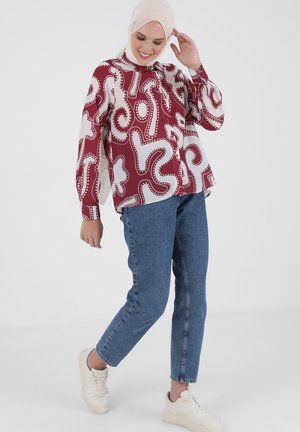 Chemise à manches longues bourgogne avec un motif abstrait blanc, associée à un jean en denim bleu clair et des baskets beiges. Tissu lisse et coupe décontractée.