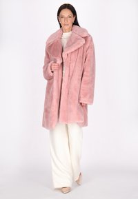 Ruzkleurige faux fur jas met een oversized kraag, knoopsluiting en lange mouwen, gecombineerd met witte wijde broekspijpen. Zachte textuur, ontspannen pasvorm.