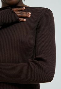 Rudas, ribuotas ilgomis rankovėmis marškinėliai su apvaliu iškirpimu. Savybės: suglamžyti kraštai rankogaliuose ir prigludęs dizainas.
