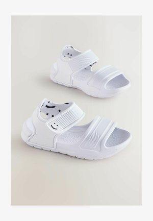 Białe sandały z regulowanymi paskami, teksturowaną podeszwą i uśmiechniętą buźką na wewnętrznej podszewce. Wykonane z gumowego materiału, z otwartym noskiem.