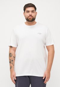 Witte katoenen T-shirt met korte mouwen, ontspannen pasvorm, ronde hals, met subtiele zwarte grafische letters op de linkerborst.