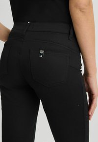 Jeans negre din denim cu un design slim-fit, detalii de cusătură subtile și un buzunar rectangular pe spate cu accesorii din argint.