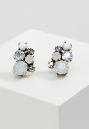 Boucles d'oreilles clous regroupées avec des pierres précieuses rondes, facettées, bleues, blanches et transparentes, montées sur métal couleur argent.