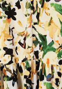 Vestido de estampado floral con una base amarilla y acentos en verde, negro y naranja, fabricado con tela texturada y botones redondos a lo largo del frente.