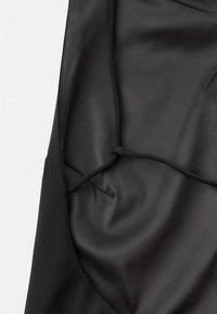 Tela negra con una textura lisa y mate, que presenta una costura y un sutil detalle de costura. El diseño es simple y funcional.