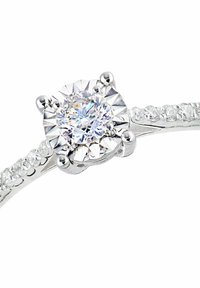 Un anello d'argento con un diamante centrale rotondo e multi-faccettato, circondato da diamanti più piccoli lungo la fascia. Finitura liscia e lucida.