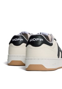 Sneakers met een gladde off-white leren bovenkant, zwarte accenten, ronde veters en een tan rubberen zool. "HOFF" logo weergegeven op de hiel.