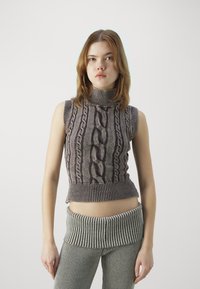 Top senza maniche lavorato a maglia con colletto alto di colore grigio, caratterizzato da motivi a treccia e orlo a costine. Abbinato a pantaloni a vita alta a coste coordinati.