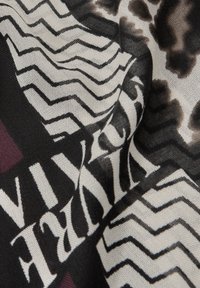 Hedvábný šátek s černobílo-burgundovým geometrickým vzorem se zigzagovými čarami a abstraktními tvary, hladká textura a splývavý design.