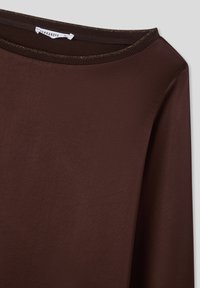 Maglietta marrone a maniche lunghe realizzata in tessuto liscio. Presenta un ampio scollo con una sottile finitura strutturata attorno al collo.