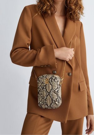 Sac à bandoulière en motif serpent beige et noir, avec une chaîne dorée et un détail de logo. Surface texturée avec une forme rectangulaire.