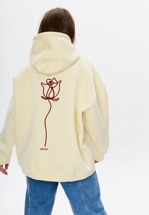 Lichtgele hoodie gemaakt van zachte stof, met een rode geborduurde rozenontwerp op de rug en een capuchon met trekkoord. Losse pasvorm.