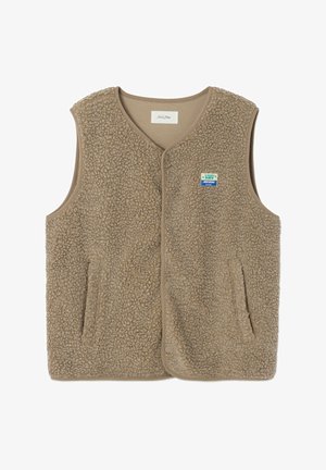 Bēšs bezroku flīsa vestes ar sprādzēm, divām priekšējām kabatām un mazu zilu un baltu plāksteri uz krūtīm.