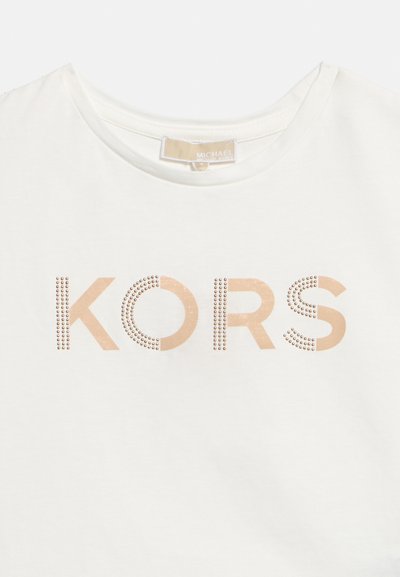 Λευκό μπλουζάκι με στρογγυλή λαιμόκοψη και την επιγραφή "KORS" σε μπεζ χρώμα, διακοσμημένο με μικρές μεταλλικές καρφίτσες στο κέντρο εμπρός.