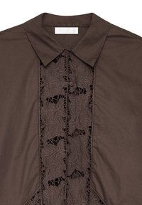 Camicia marrone con colletto caratterizzata da dettagli in pizzo intricati lungo la parte anteriore, con due bottoni e una texture di tessuto liscia.