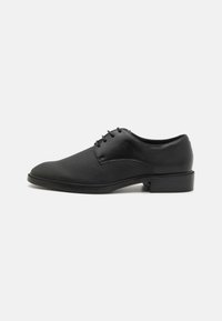 Black leather dress shoe with a smooth finish, rounded toe, lace-up design, and a low, rectangular heel. Textured upper with subtle stitching.
