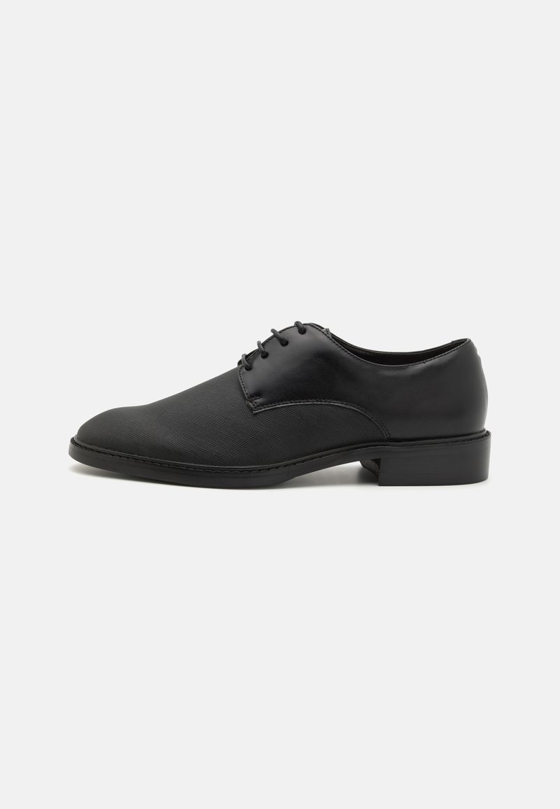 Black leather dress shoe with a smooth finish, rounded toe, lace-up design, and a low, rectangular heel. Textured upper with subtle stitching.