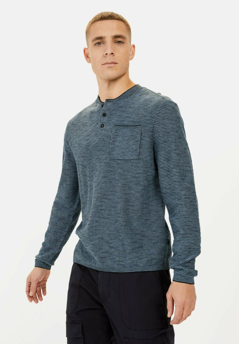 Langärmliges Henley-Shirt in Blau mit horizontalen Streifen, ausgestattet mit einer Knopfleiste und einer aufgesetzten Tasche auf der linken Brust. Texturiertes Material.