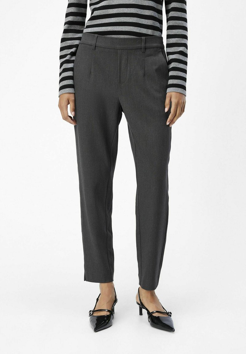 Dark gray tailored trousers with a smooth texture and side pockets, paired with black pointed-toe heels and a black-and-gray striped top.