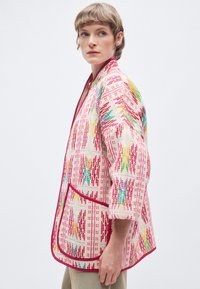 Πολύχρωμο, εμπριμέ μπουφάν με μπεζ βάση, που διαθέτει ροζ, πράσινες και πορτοκαλί αποχρώσεις. Περιλαμβάνει εμπρόσθια τσέπη και μανίκια τριών τετάρτων.
