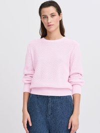 Hellrosa gestrickter Pullover mit strukturiertem Muster, Rundhalsausschnitt und gerippten Bündchen. Kombiniert mit dunkelblau gestreiften weiten Hosen.