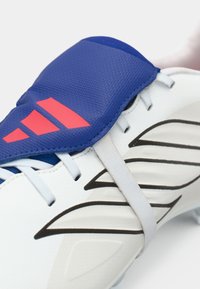 Ποδοσφαιρικό παπούτσι με λευκή βάση, υφασμένο μπλε και ροζ επάνω μέρος, ελαστικό λουράκι και μαύρες ακμές στις πλευρές.