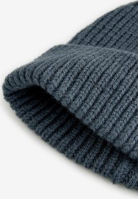 Gorro de punto acanalado gris oscuro con dobladillo. Fabricado en hilo suave, presenta un patrón texturizado y un ajuste ceñido para aportar calor.