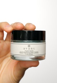 Klar glasburk med ett svart lock, med en vit etikett med svart text som säger "avant", innehållande en ljusblå behandling för akne och orenheter.