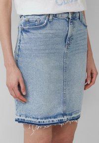 Lichtblauwe denim rok met een getailleerd ontwerp, een rafelige zoom en traditionele vijf-pocketstijl, voorzien van koperen hardware accenten.