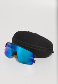 Gafas de sol negras con grandes lentes espejadas en azul y rosa, con un diseño contorneado y un marco negro mate, al lado de un estuche negro con cremallera.