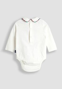 Baltos ilgomis rankovėmis kūdikių bodysuit'as su trimis sagomis nugaros dalyje ir mažu Peter Pan tipo apykakle su kailiniu apvadu ant vieno tono fono.