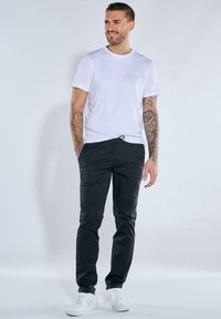 White short-sleeve T-shirt, black drawstring pants, and white sneakers. Features smooth fabric, slim fit, and minimalistic design.