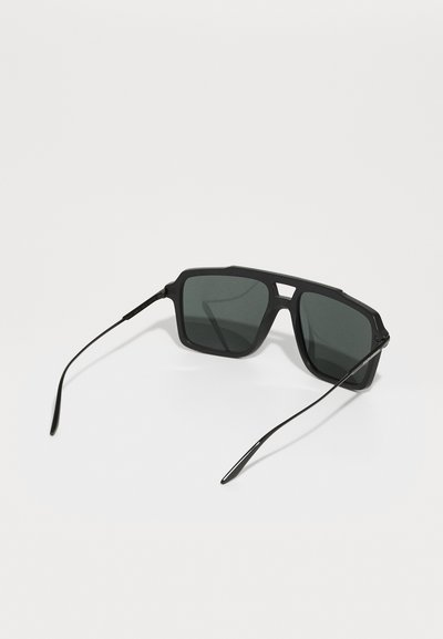 Ochelari de soare negri cu un cadru geometric, unghiular, lentile întunecate și brațe subțiri negre. Design minimalist cu un finisaj mat și fără branding vizibil.