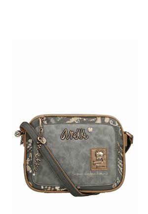 Bolso cruzado sintético gris con una textura similar al cuero, presenta una correa beige, un logo en relieve y detalles de hardware con temática de gatos.