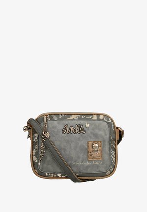 Bolso cruzado sintético gris con una textura similar al cuero, presenta una correa beige, un logo en relieve y detalles de hardware con temática de gatos.