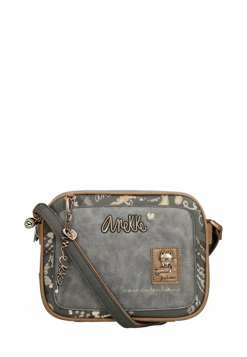 Bolso cruzado sintético gris con una textura similar al cuero, presenta una correa beige, un logo en relieve y detalles de hardware con temática de gatos.