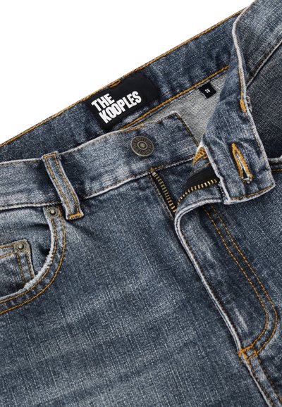 Jeans de mezclilla azul oscuro con costuras en contraste naranja, que presentan un cierre de cremallera, un botón metálico y una etiqueta que dice "THE KOOPLES."
